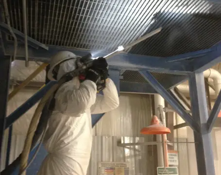 A man in white suit working on ceiling.