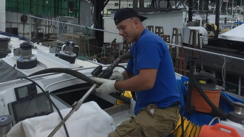 A man in blue shirt and white gloves holding on to ropes.